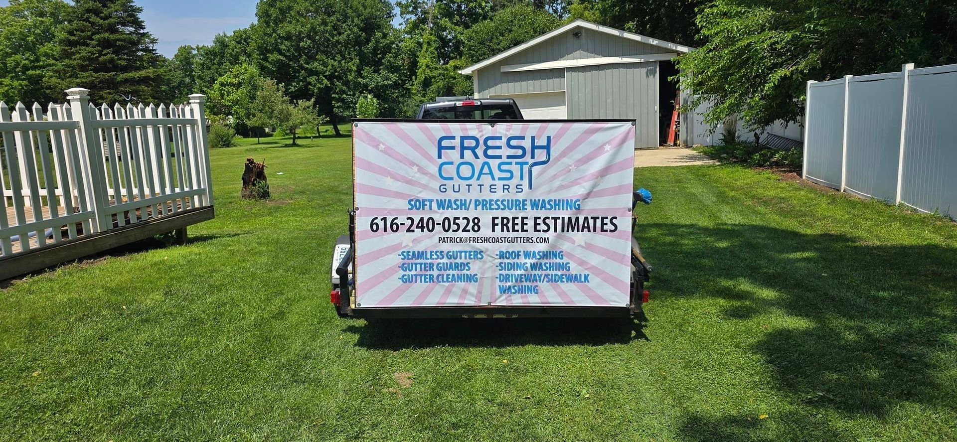 A trailer with a sign on it is parked in front of a house.