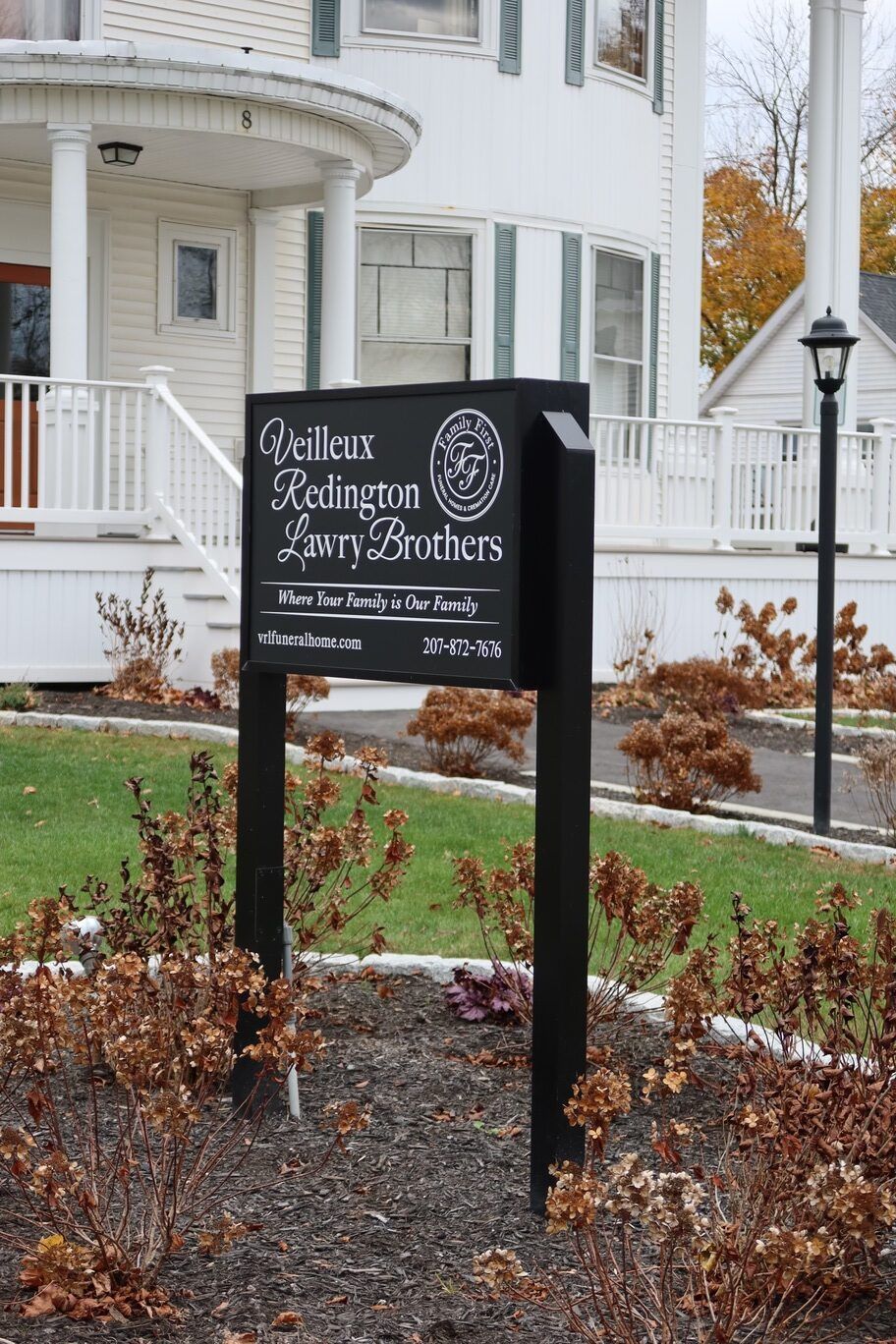 Black sign for Willow Ridge and Larry Brothers in front of a white building with fall foliage.
