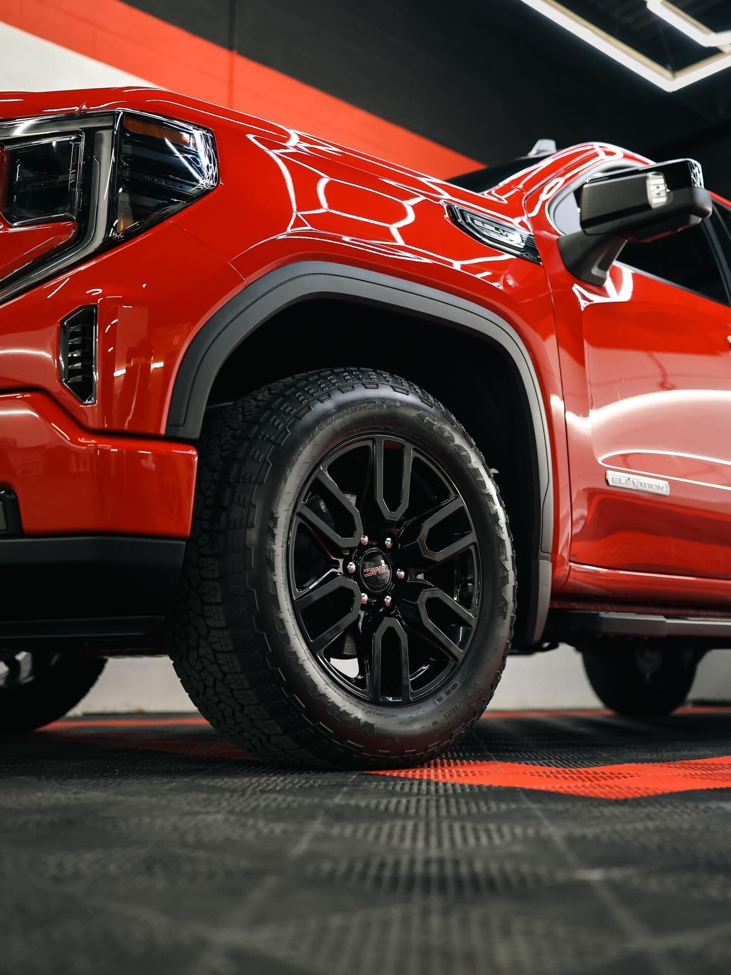Dark gray GMC Yukon SUV with chrome wheels parked in a garage.