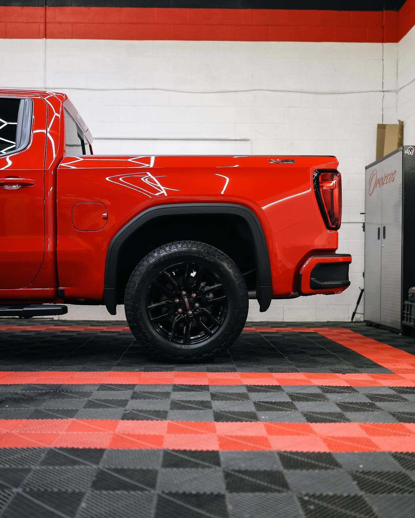 Black Acura sedan parked in a garage with red accents, on a patterned floor.