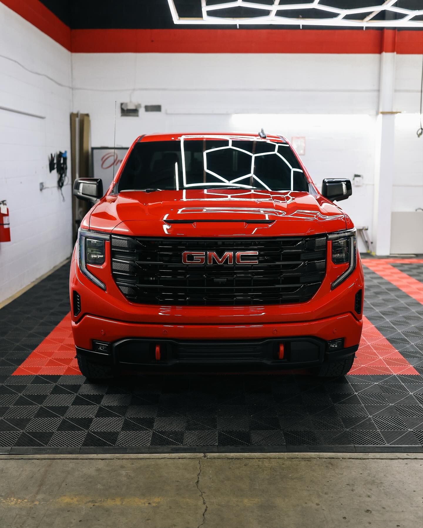 Dark gray GMC Yukon SUV with chrome wheels parked in a garage.
