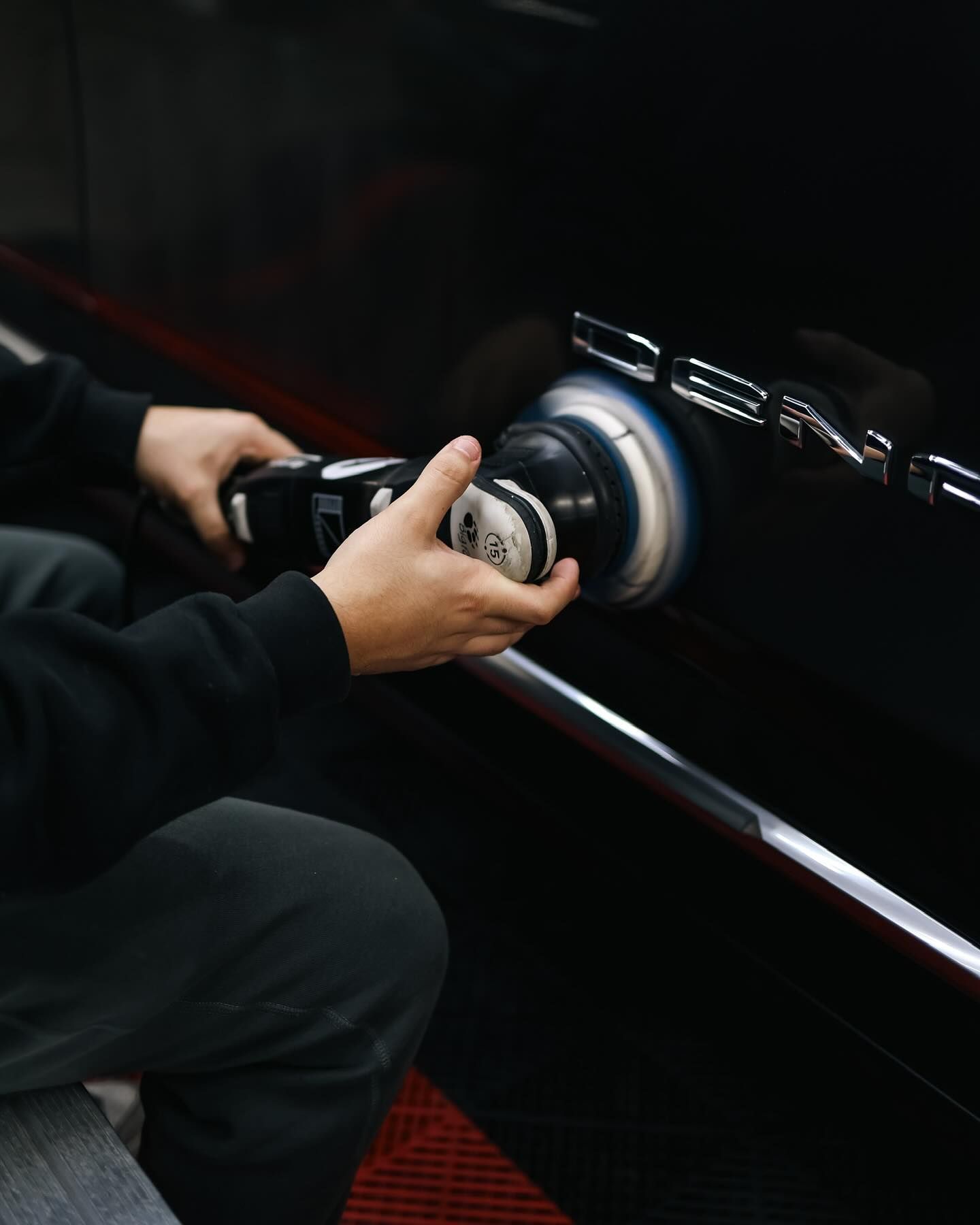 Technician performing automotive paint correction on a black vehicle