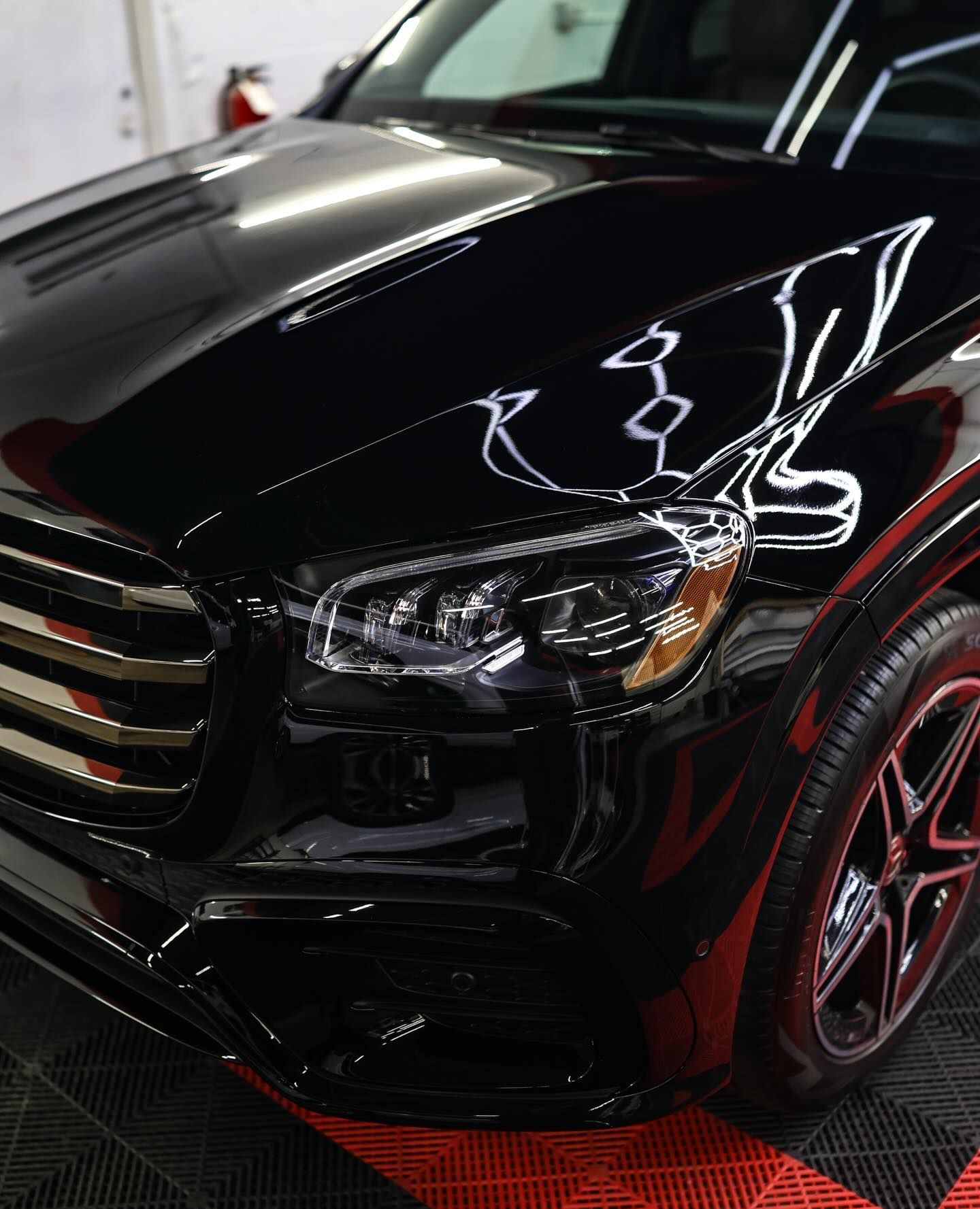 White car with gold rims on a red and black floor, against a white and black wall.