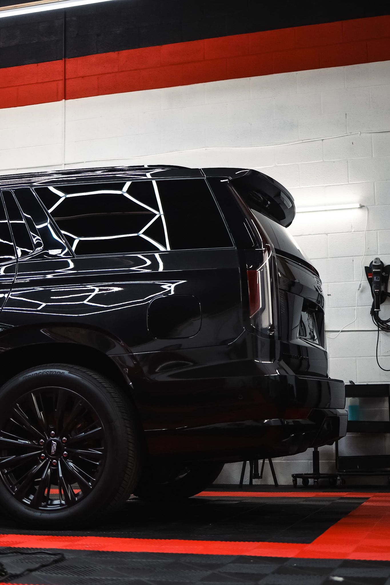 A blue car with black wheels and tires is parked in a garage.