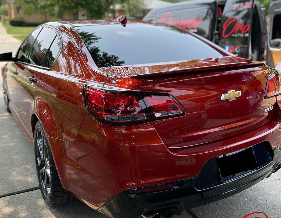 A red chevrolet sedan is parked on the side of the road.