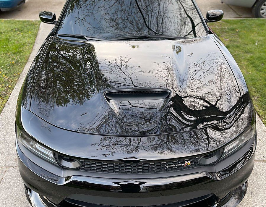 a black dodge charger is parked on a sidewalk in a driveway .