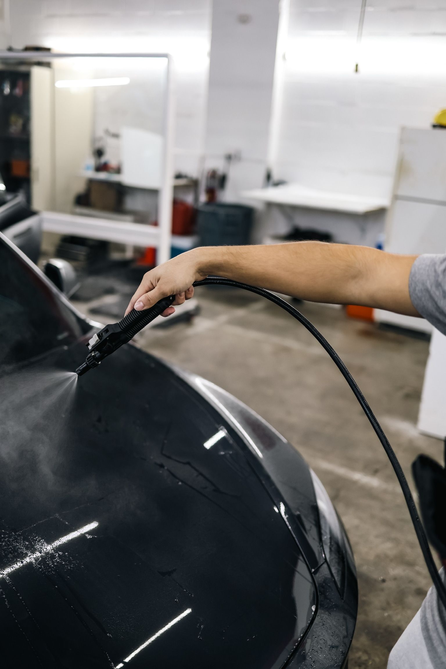 Black Acura sedan parked in a garage with red accents, on a patterned floor.