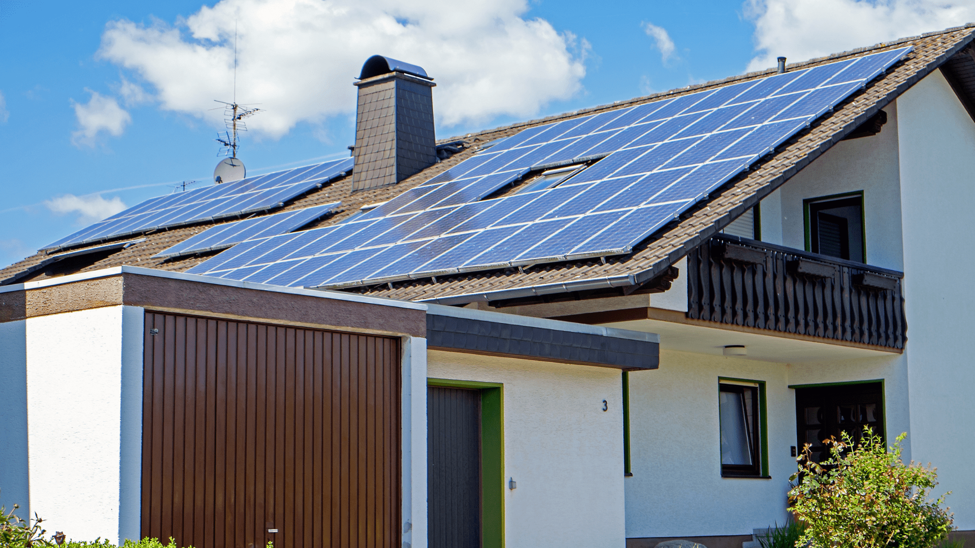 House with solar panels on roof, blue sky, and garage — OzEnergi in Caloundra West, QLD