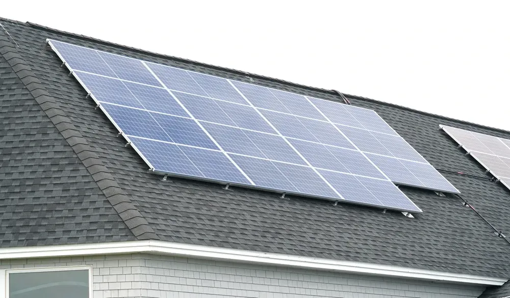 Solar panels on a dark shingled roof, angled towards the sky, generating renewable energy. — OzEnergi in Pimpama, QLD