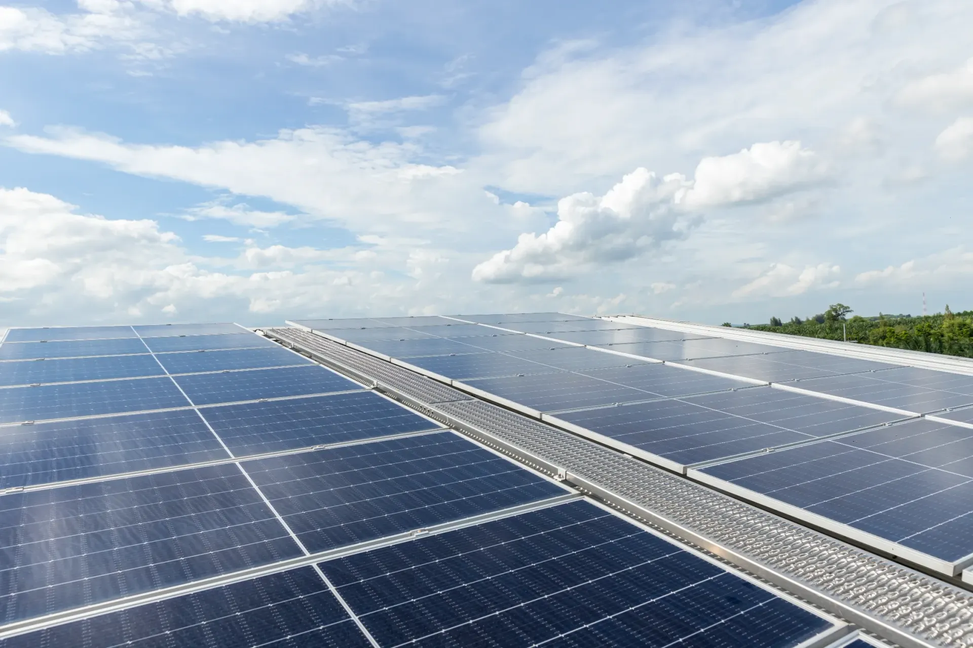 Solar panels on a rooftop against a cloudy blue sky. — OzEnergi in Beenleigh, QLD