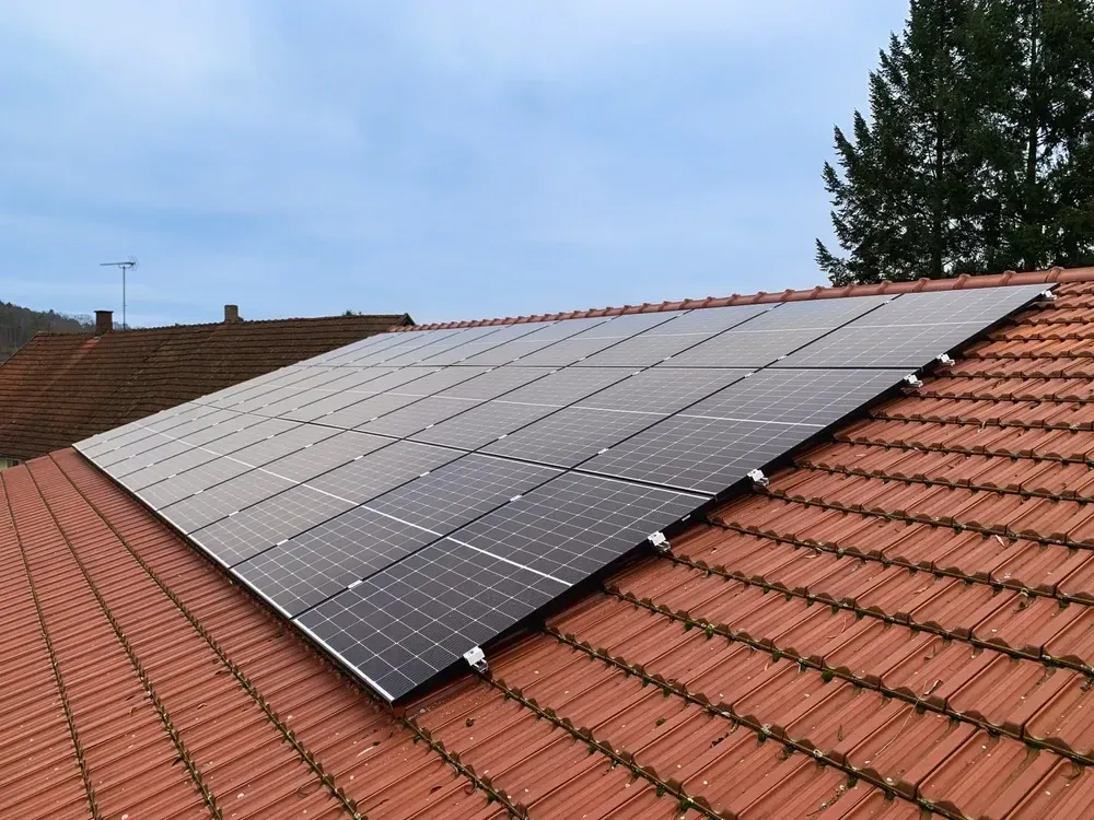Solar panels installed on a red tile roof against a cloudy sky. — OzEnergi in Beenleigh, QLD