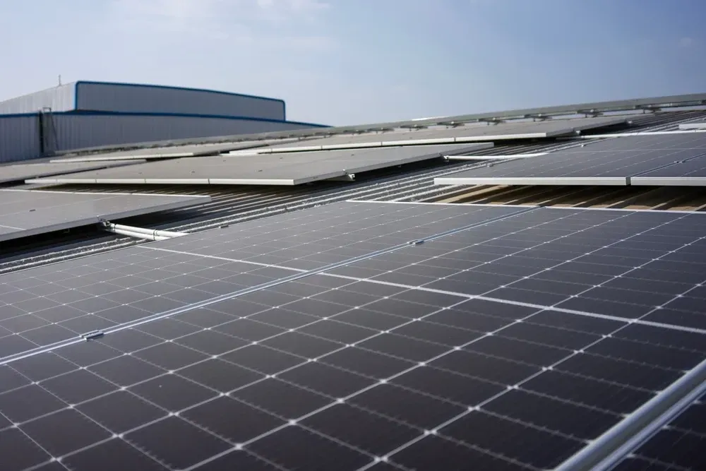Solar panels installed on a commercial building roof against a bright sky. — OzEnergi in Mermaid Beach, QLD
