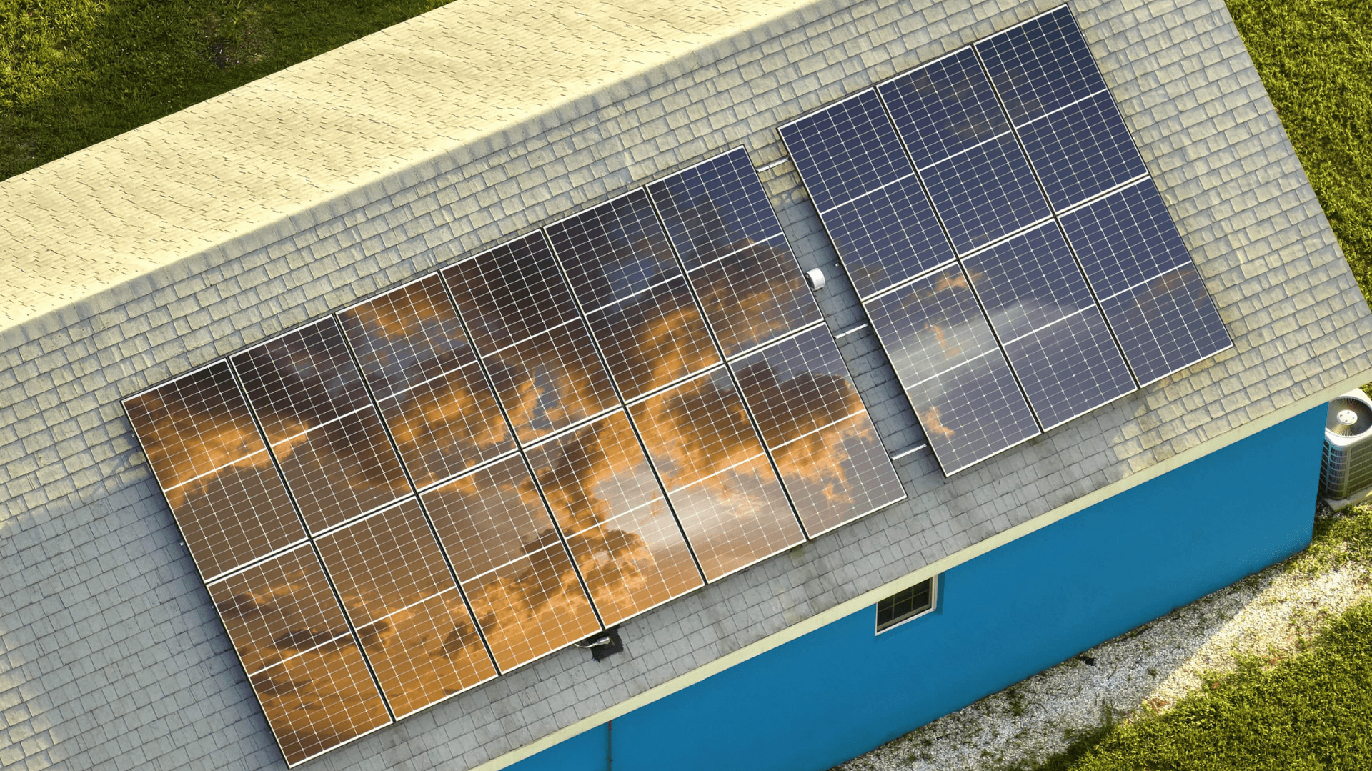Solar panels on a blue building's roof reflect the sky — OzEnergi in Caloundra West, QLD
