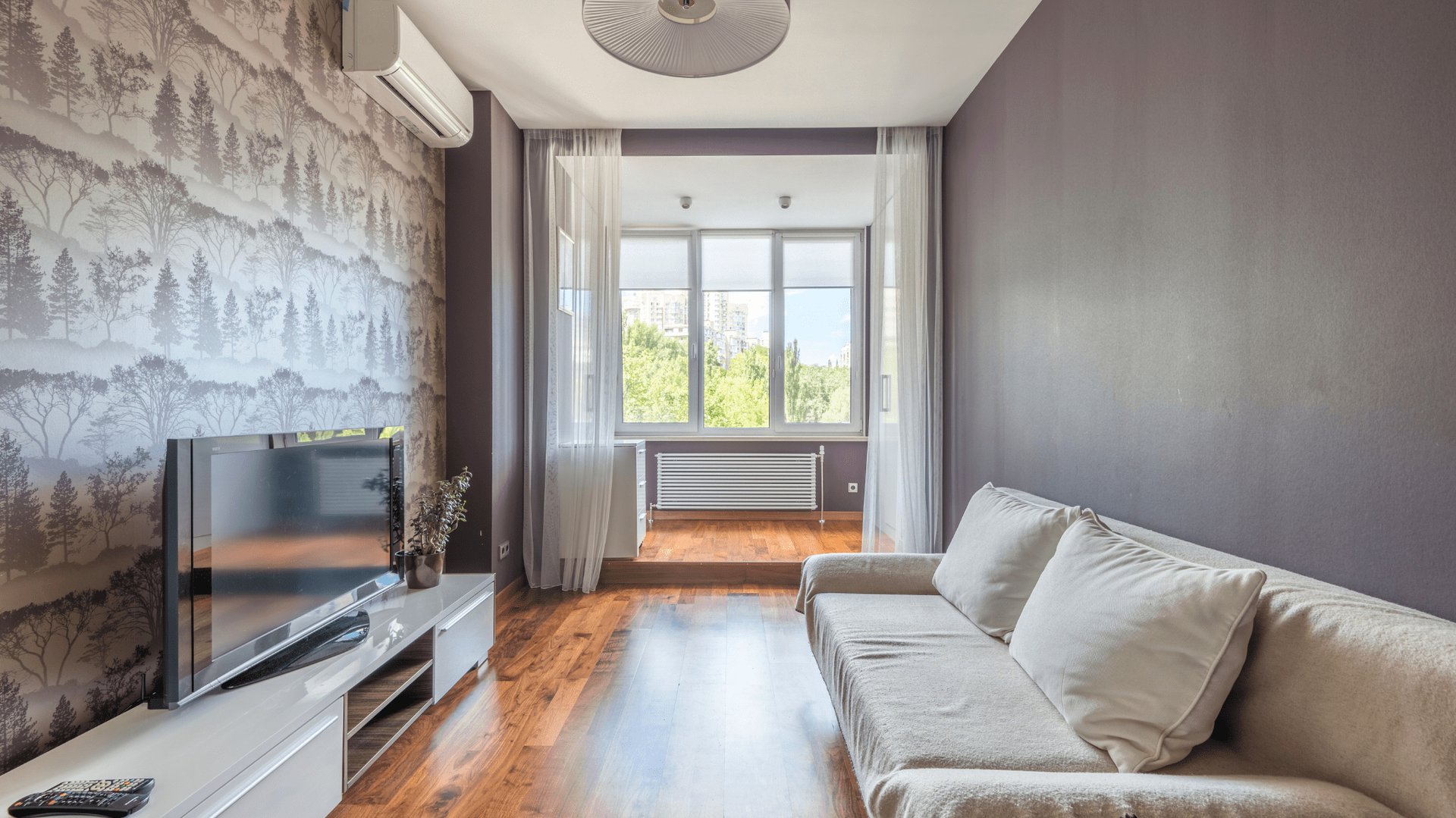 Living room with white sofa, TV, and heat pump — OzEnergi in Caloundra West, QLD