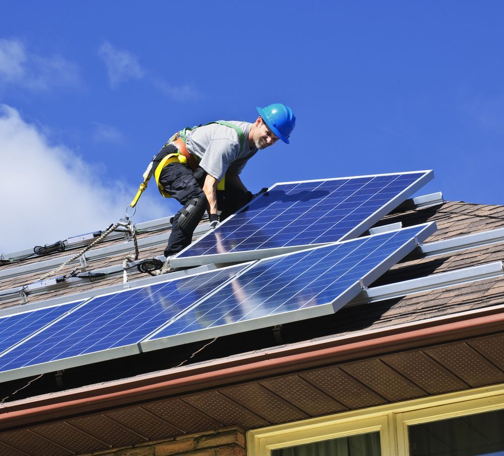 Worker in Blue Hard Hat Installing Solar Panels — OzEnergi in Caloundra West, QLD