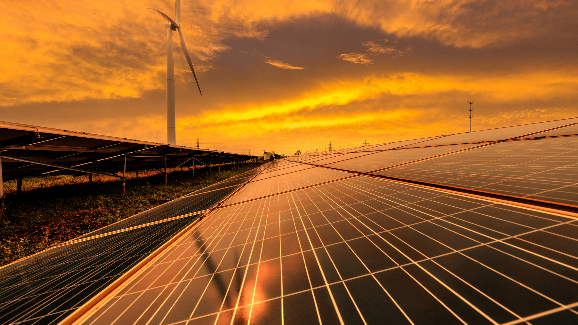 Solar panels and wind turbine under an orange sunset sky — OzEnergi in Caloundra West, QLD