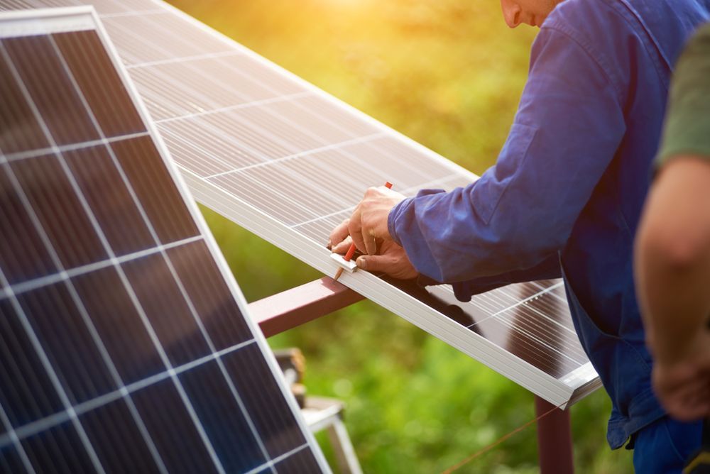 Worker in Blue Shirt Installing Solar Panels Outdoors — OzEnergi in Pimpama, QLD