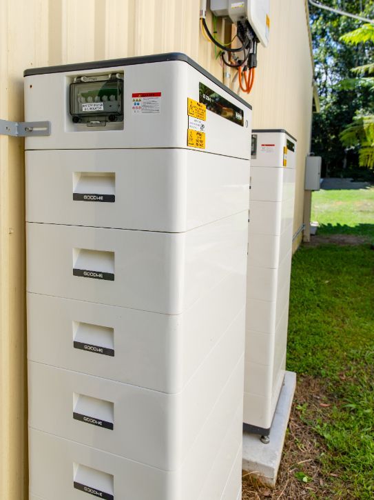 White Energy Storage Container with A Solar Panel on A Grassy Field with Trees Under a Blue Sky — OzEnergi in Caloundra West, QLD