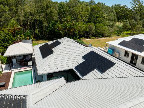 Worker in Blue Shirt Installing Solar Panels Outdoors — OzEnergi in Pimpama, QLD