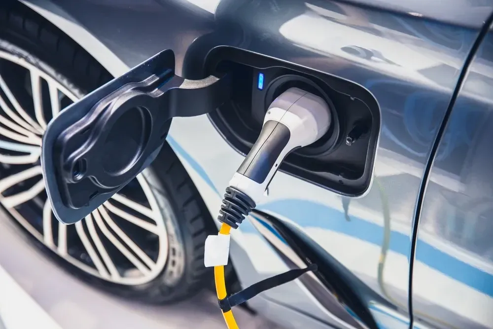 Electric car charging, charging port open with cable connected, blue car exterior, close-up. — OzEnergi in Nerang, QLD