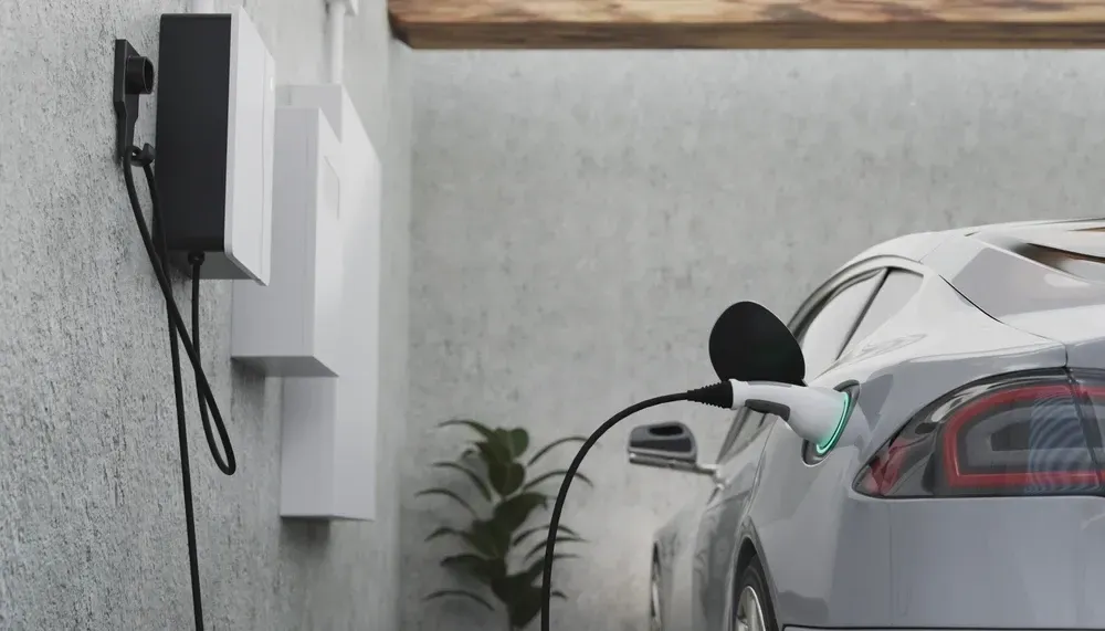 Electric car charging at a home charging station. White car plugged in, charging on a textured wall. — OzEnergi in Robina, QLD