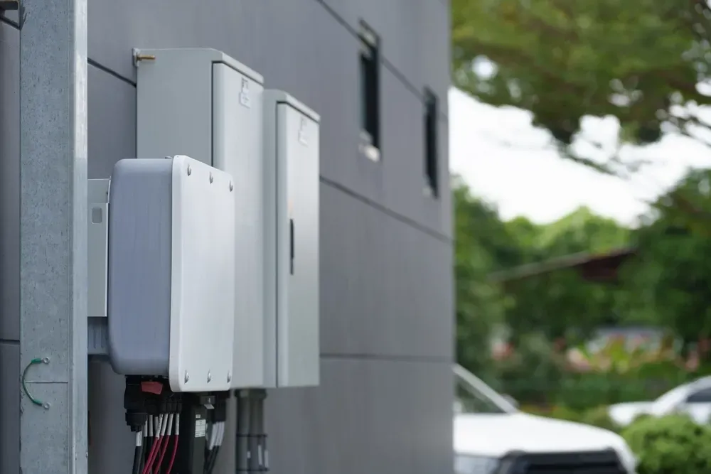 Three gray electrical boxes mounted on a gray building exterior. — OzEnergi in Robina, QLD