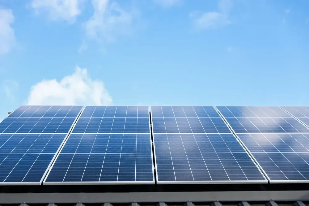 Solar panels on a rooftop with a bright blue sky and clouds in the background. — OzEnergi in Robina, QLD