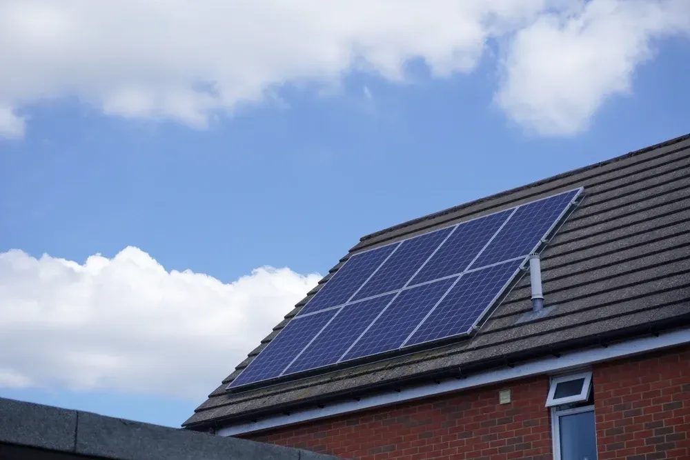Solar panels on a residential roof against a blue sky with fluffy clouds. — OzEnergi in Southport, QLD