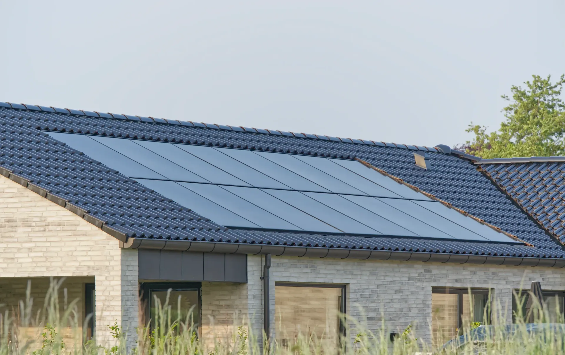 Solar panels installed on a dark tiled roof of a light brick house. — OzEnergi in Coomera, QLD