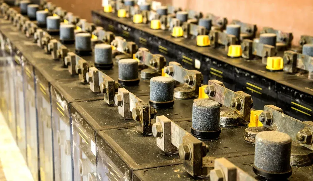 Rows of old, industrial-looking batteries, black with gray and yellow details, likely used for power storage. — OzEnergi in Nerang, QLD