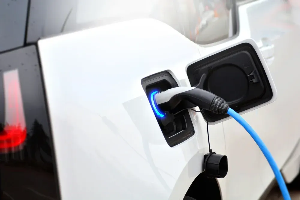 White electric car being charged with a blue charging cable. — OzEnergi in Southport, QLD