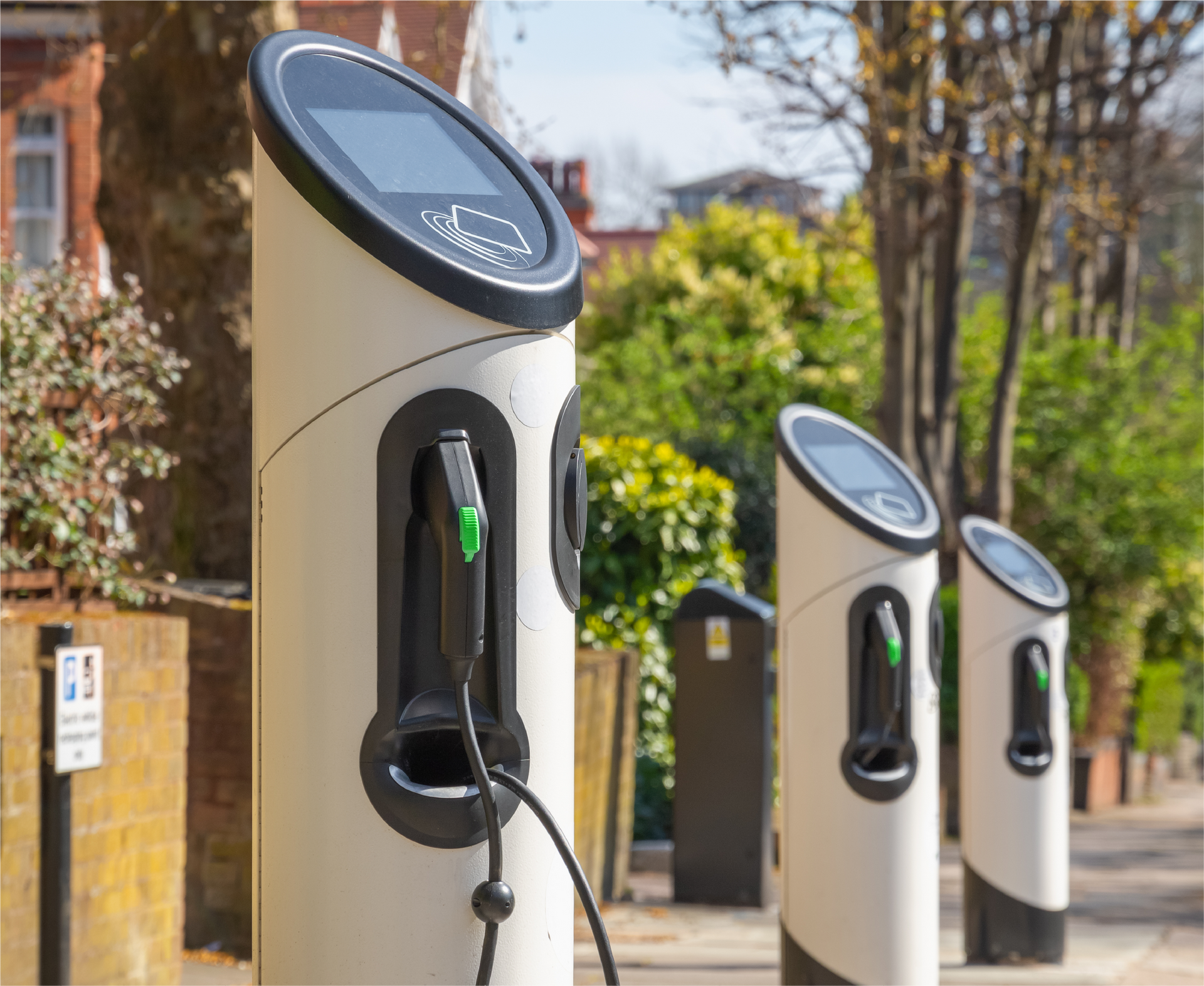 A row of electric vehicle charging stations on a sidewalk.