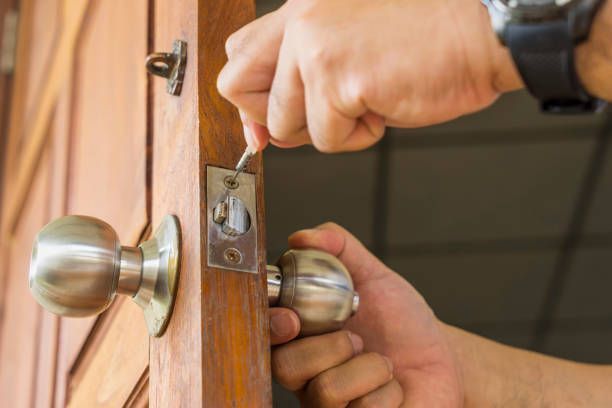 A man is fixing a door knob with a screwdriver.
