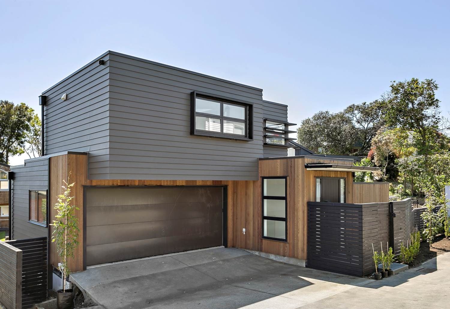 Modern two-story house with gray siding, wooden accents, and a garage.
