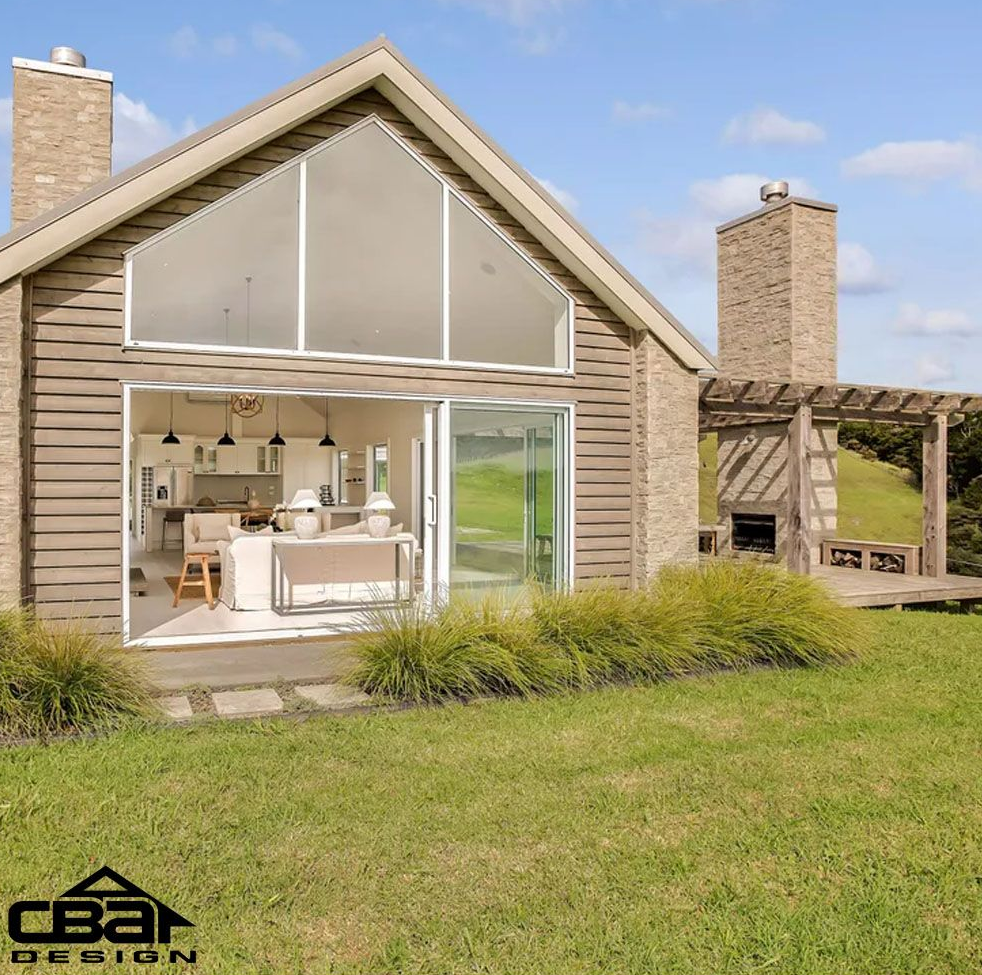 Modern house with large windows, brick chimney, and open sliding doors onto a green lawn.