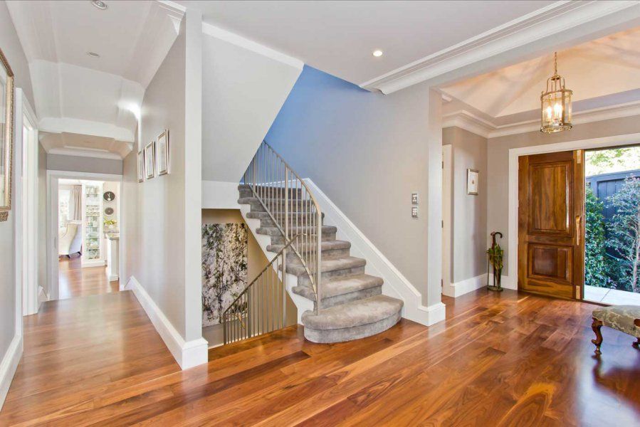 Hallway with wooden floor, staircase, and open front door.