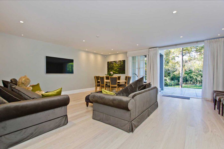 Spacious living room with gray sofas, dining table, and sliding glass doors to a backyard.