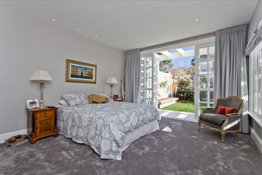 Bedroom with bed, nightstands, chair, sliding doors to a garden, and gray carpet.