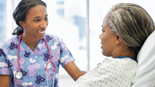 A nurse is talking to a patient in a hospital bed.