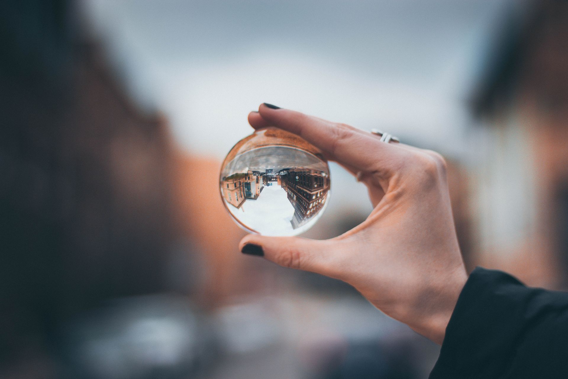 Hand holding a crystal ball, reflecting a blurred outdoor scene.