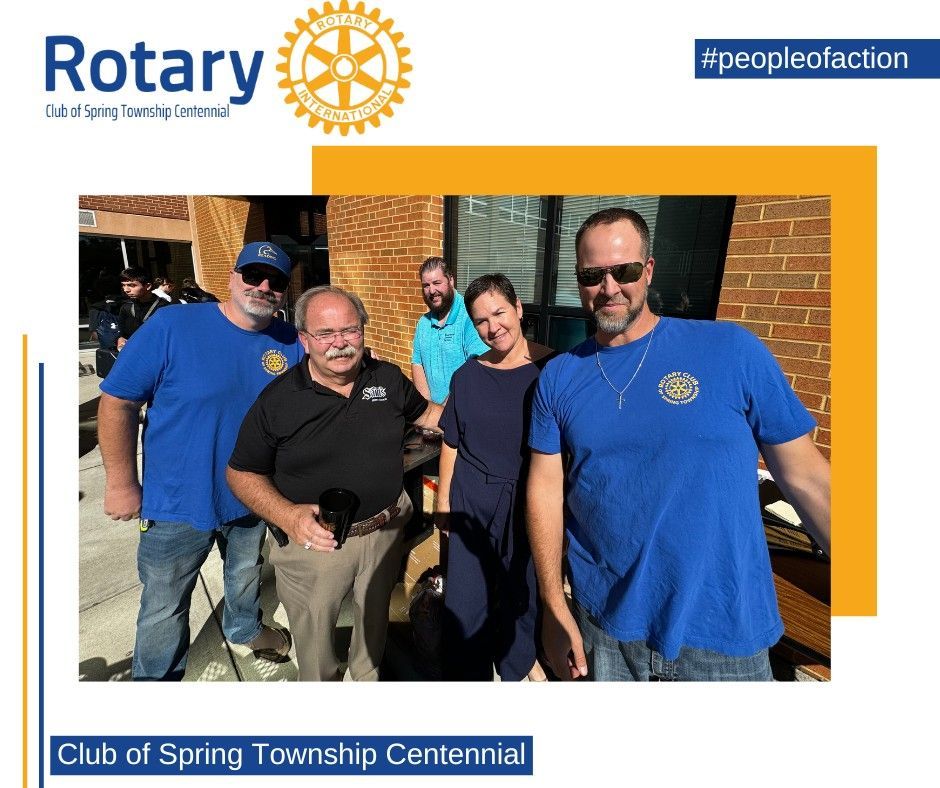 A group of people are posing for a picture in front of a rotary logo.