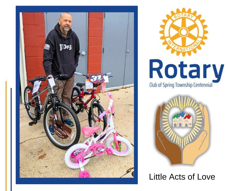 A man is holding a bicycle in front of a rotary logo.