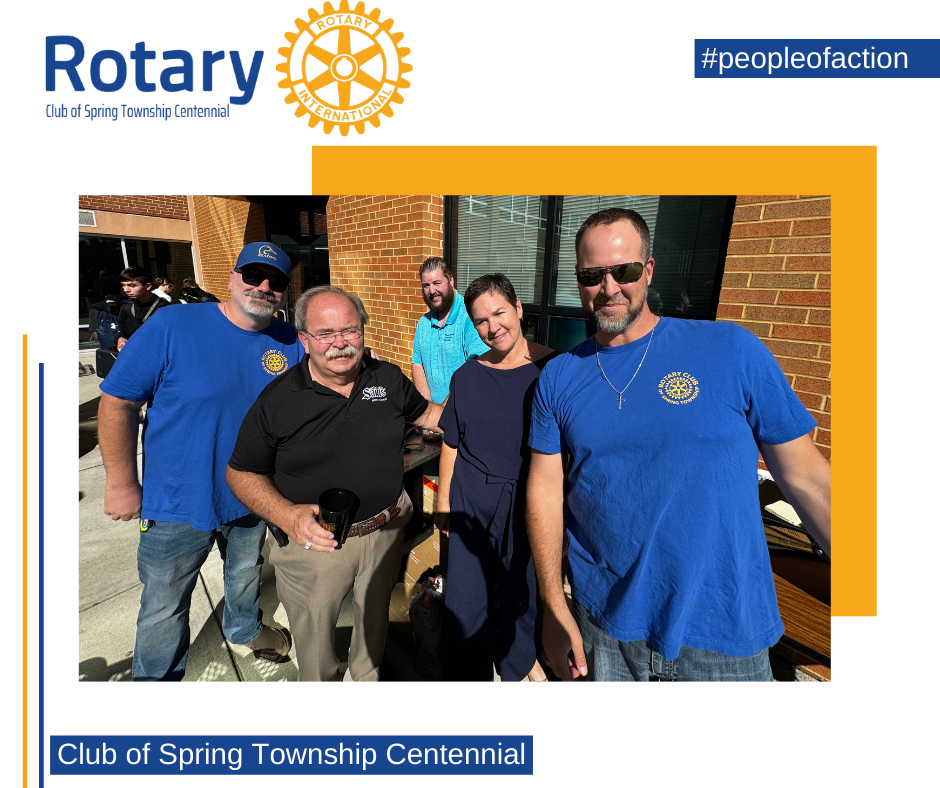 A group of people are posing for a picture in front of a rotary logo.