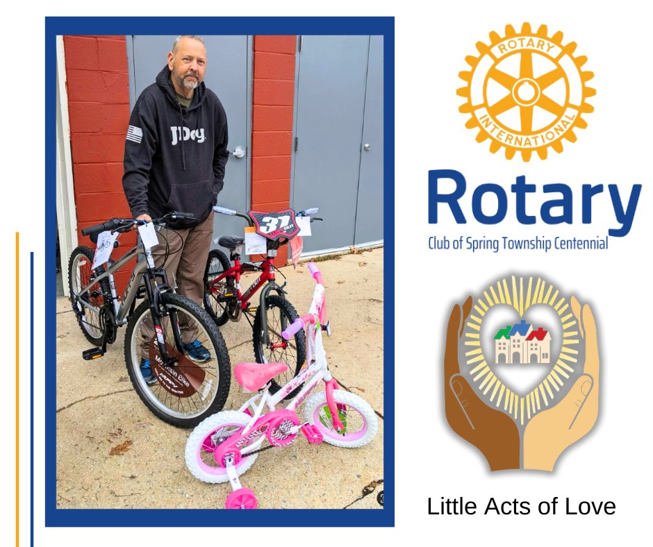 A man is holding a bicycle in front of a rotary logo.