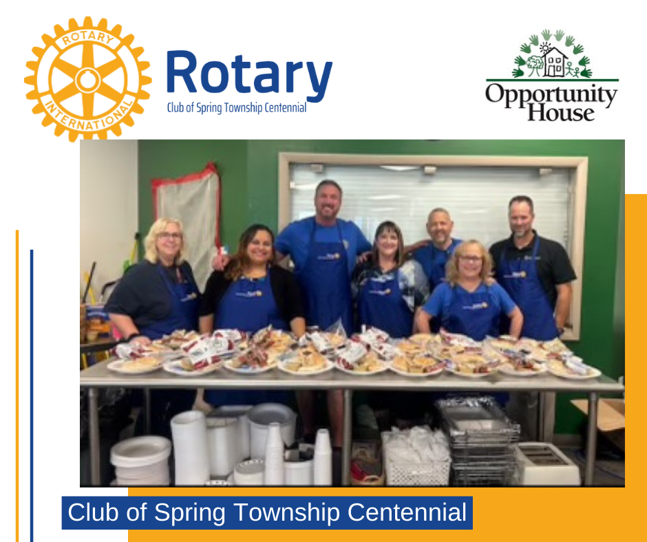 A group of people standing around a table with plates of food.