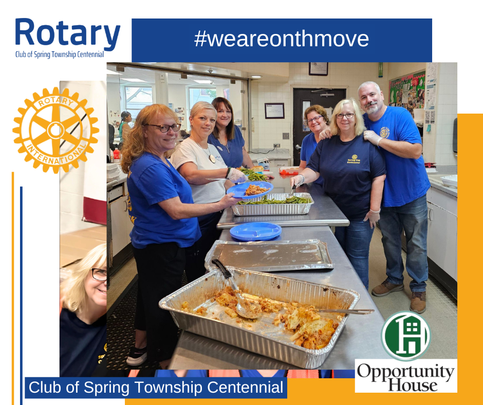 A group of people standing around a table with trays of food.