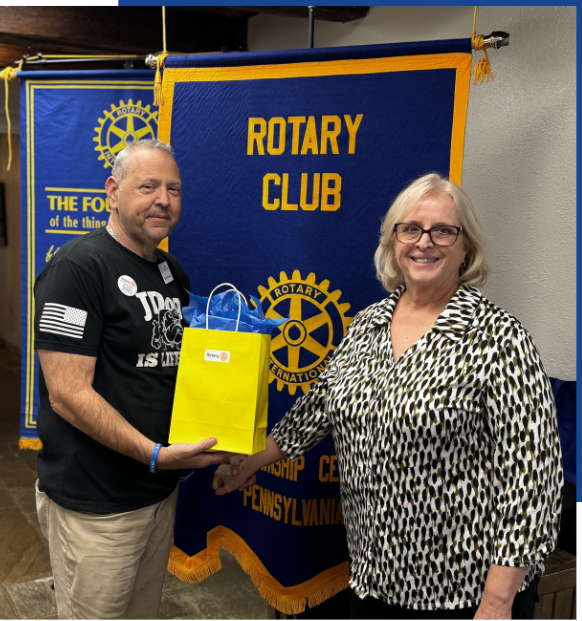 Two people standing in front of a banner that says rotary club