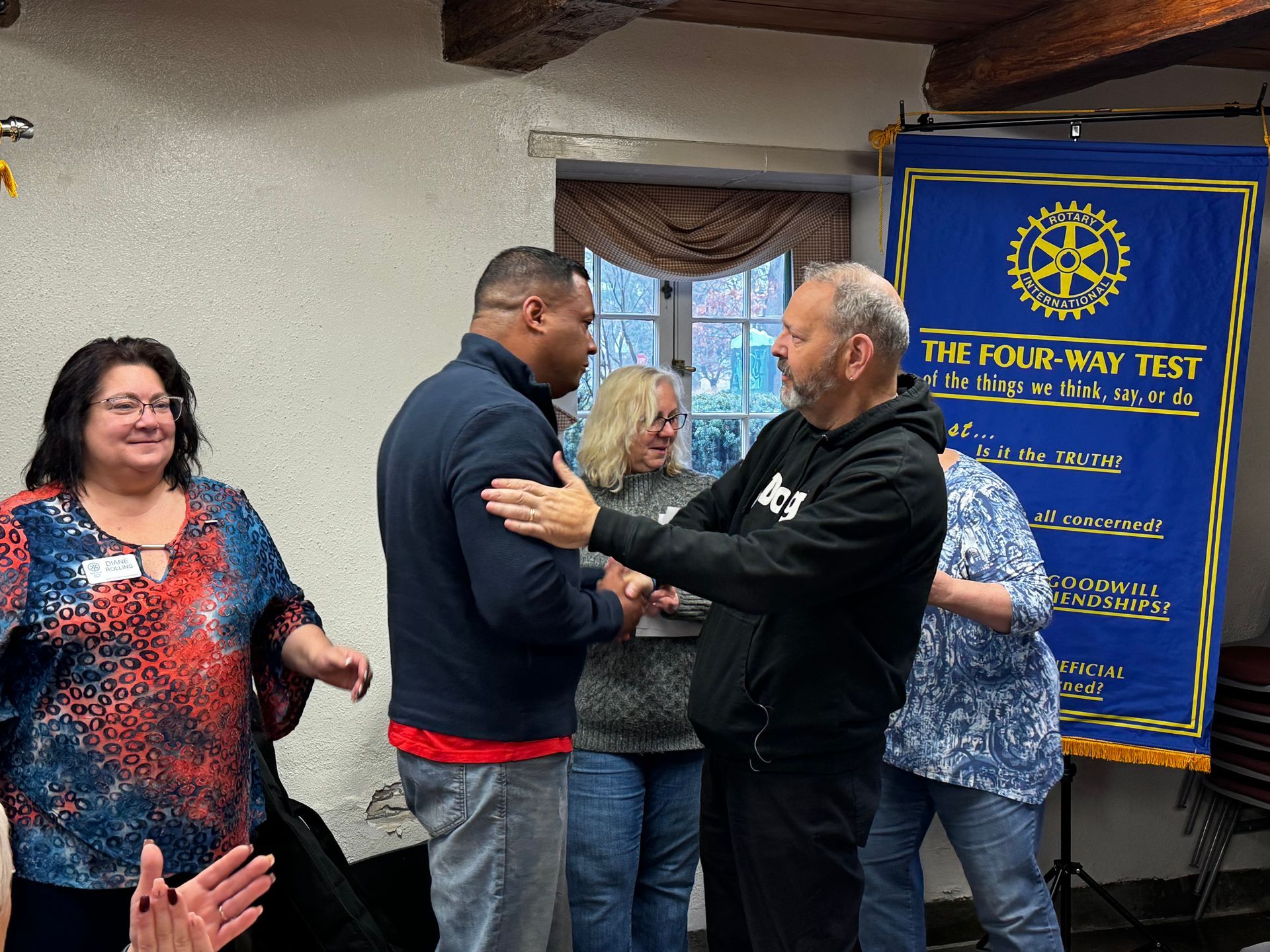 A group of people are standing in front of a banner that says the four way test
