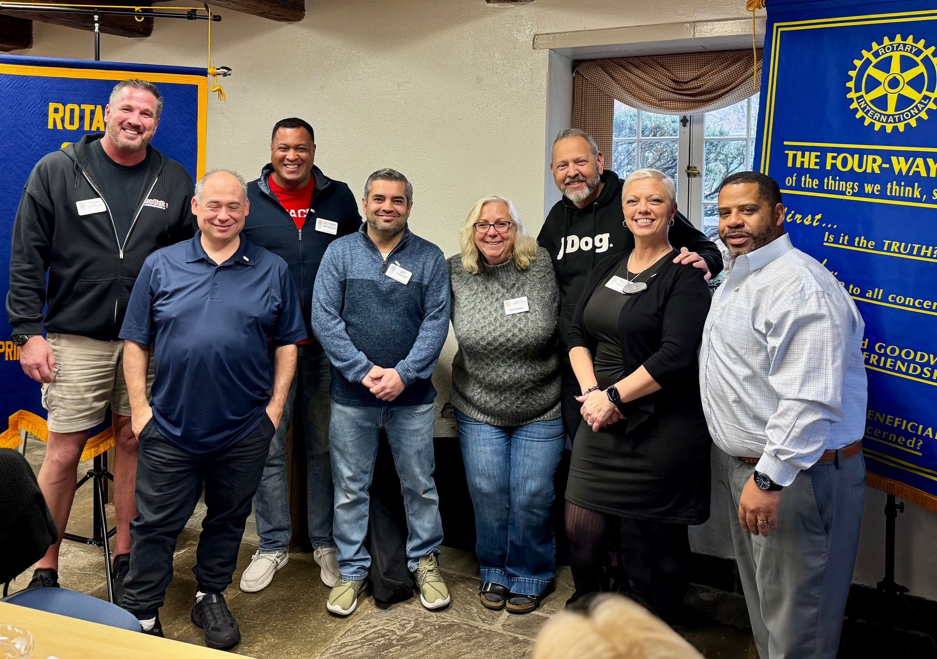 A group of people are posing for a picture in front of a rotary banner.
