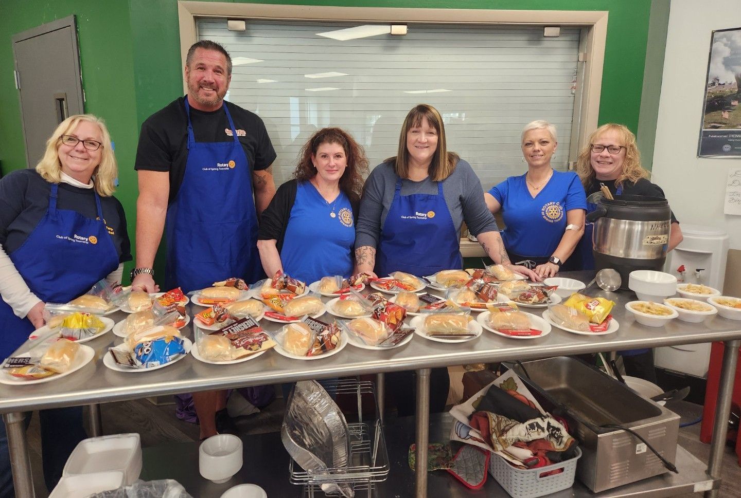 A group of people are standing around a table filled with food.